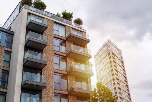Modern apartments with spacious balconies and rooftop gardens under a cloudy sky, emphasizing green living.